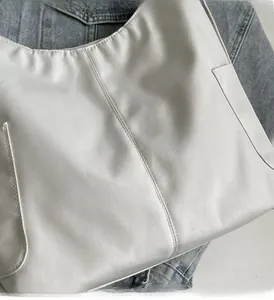 Detailopname van een lichtgrijze lichtgewicht draagtas met stiksels en gladde nylon textuur