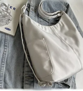Minimalistische witte schoudertas met verstelbare riem op blauwe denim achtergrond