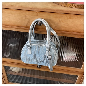 Close-up of light blue denim pillow bag with wavy silver sequins and dual handles