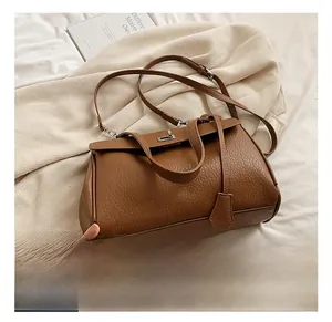 Detail of brown lychee grain leather shoulder bag with metallic buckle and hangtag
