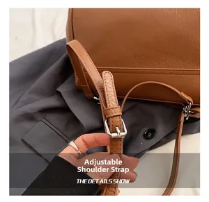 Detail of adjustable shoulder strap with silver buckle on brown lychee leather bag
