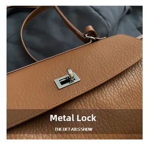 Detail of silver twist lock on brown lychee grain leather underarm bag