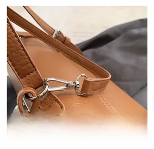 Detail view of durable silver metal buckle and brown lychee grain leather handbag strap