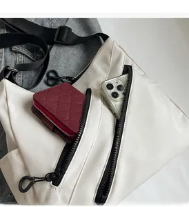 Close-up of the multiple zipper pockets and large interior space of the white canvas bag