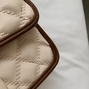 Dettaglio della borsa trapuntata beige con cuciture e finitura dei bordi in pelle marrone