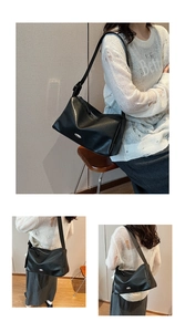 Detail of black rectangular underarm bag with metal plate and adjustable strap