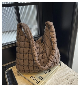 Detailed view of brown quilted tote bag with soft puffy texture and wide handles