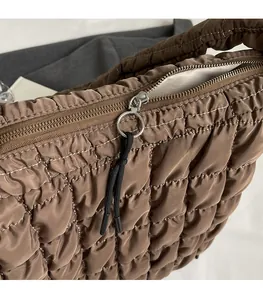 Detailed close-up of a silver ring zipper and woven drawstring on a brown quilted tote bag