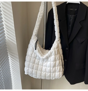 Detail of white quilted puffy cloud bag showing soft polyester texture and zipper detail