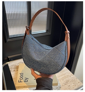 Detail view of denim crescent bag with silver stud lattice and brown leather strap