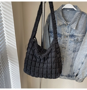 Detail of black quilted hobo bag featuring square stitching and glossy nylon fabric