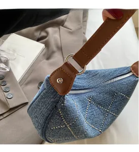 Dettaglio della borsa denim con borchie argentate a rombi e tracolla in pelle