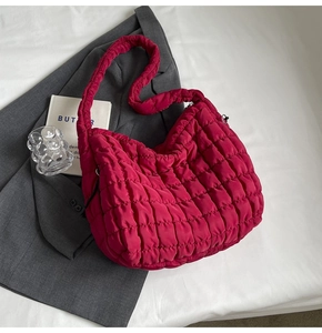 Detailed view of magenta quilted puffer tote bag on a grey blazer over white fabric