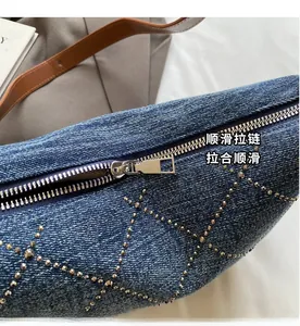 Dettaglio della cerniera liscia e dei rivetti sulla borsa ascellare in denim