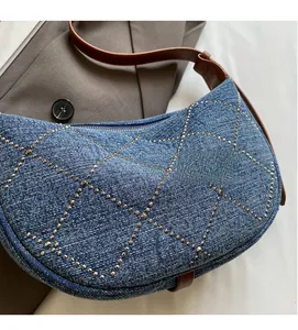 Dettaglio della borsa a mezzaluna in denim con strass a rombi e tracolla in pelle scura