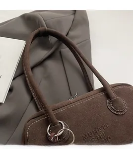 Detail of dark brown matte suede shoulder bag featuring silver buckle and logo embossment