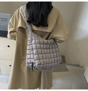 Close-up of a grey quilted bubble tote bag worn with a stylish khaki trench coat
