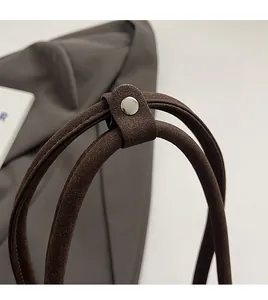 Close-up of dual shoulder straps with silver metal rivet and matte brown leather handle