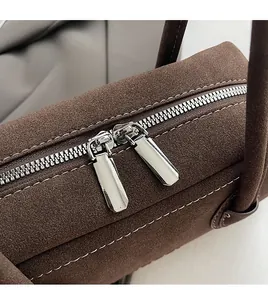 Detail of silver double zippers and white contrast stitching on a brown suede Boston bag