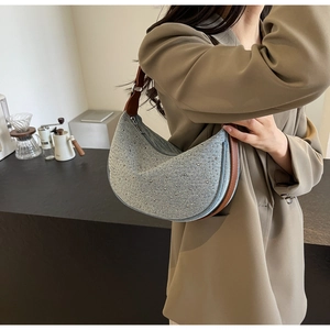 Detail of light blue rhinestone hobo bag with brown leather strap and silver metal buckle