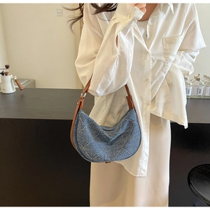 Detail of blue denim hobo bag with silver rivet quilted pattern and brown strap