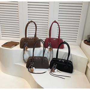Detail of matte shoulder bags in multiple colors with baseball charms on white display