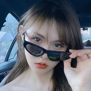Chic black cat eye sunglasses with twisted temples worn by a woman inside a vehicle