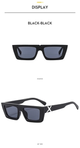 Close-up of black square sunglasses featuring a white X-shaped detail on the temple