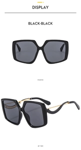 Detail of oversized butterfly sunglasses with hollow golden metal temples and black frame
