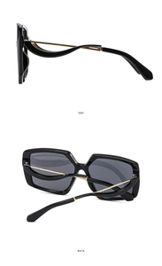 Detail of oversized black sunglasses featuring unique wavy gold metal temples in side view