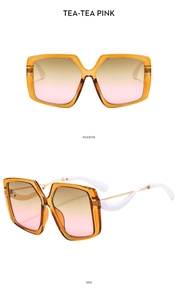 Detail view of oversized tea-colored butterfly sunglasses with wave-patterned side temples
