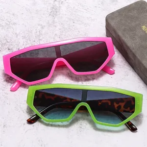 Neon pink and green oversized shield sunglasses with leopard print frame on stone surface
