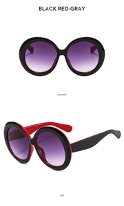 Close-up of round frame sunglasses with black frames, red inner legs and gradient lenses