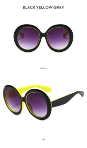 Close-up of oversized round sunglasses with black and yellow frames and purple gradient lenses