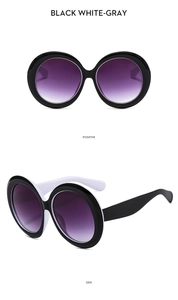 Detail view of round oversized sunglasses with black-white frames and purple gradient lenses