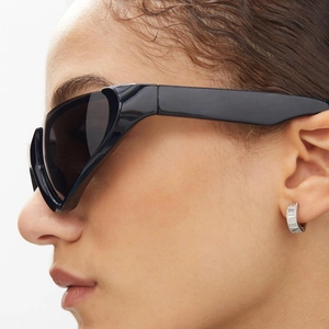 Futuristic black Y2K sports sunglasses and silver engraved ear cuff on a female model