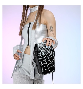 Detail of glossy black PU leather crossbody bag with white spider web print and charm