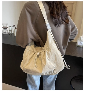 Detailed close-up of a beige large-capacity crossbody bag with pleated fabric and drawstring