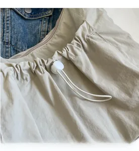 Detailed view of beige drawstring bag with textured fabric and white cord lock closure