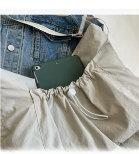 Detailed view of spacious beige crossbody bag featuring tablet storage and drawstring design