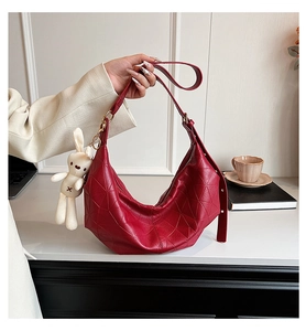 Detail of red geometric hobo bag with plush rabbit charm and wide shoulder strap