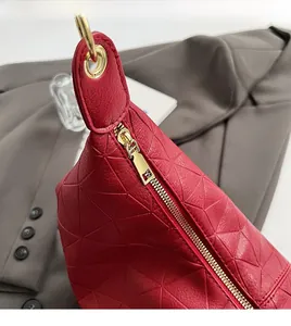 Detail of red geometric quilted PU leather bag featuring a smooth gold metal zipper