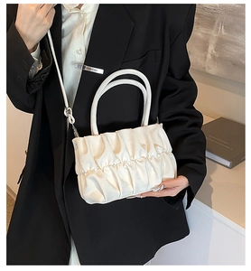 Detailed view of white pleated cloud bag with satin finish and elegant carry handle