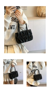 Detail of black pleated cloud handbag with soft leather texture and double top handles