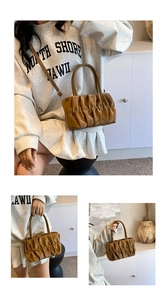 Detailed view of the wavy pleated texture and handle of the brown cloud handbag