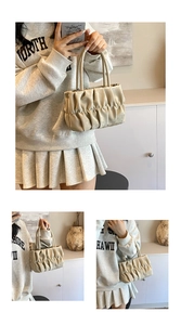 Detail of beige pleated handbag showing soft matte leather texture and dual top handles