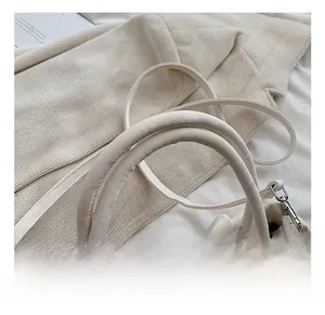 Detail view of cream white pleated hobo bag with top handles and silver zipper closure