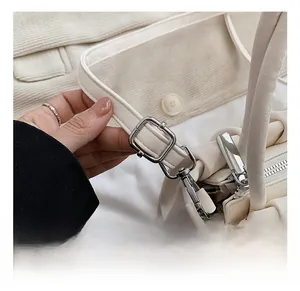 Detail of adjustable shoulder strap with silver buckle on a white ruched handbag