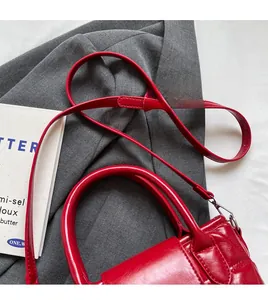 Detail of red quilted bucket bag featuring a smooth handle and adjustable silver buckle strap