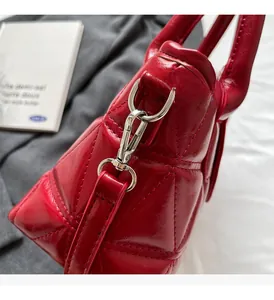 Detail of red quilted bucket bag featuring glossy finish and silver metal hardware hook